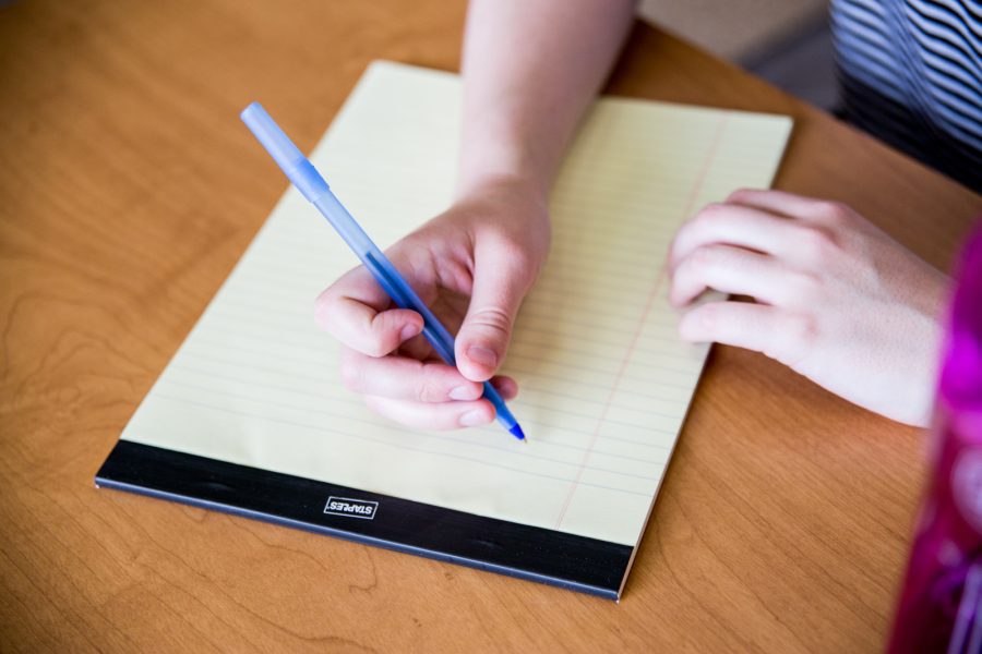 A person writes on a piece of lined notebook paper