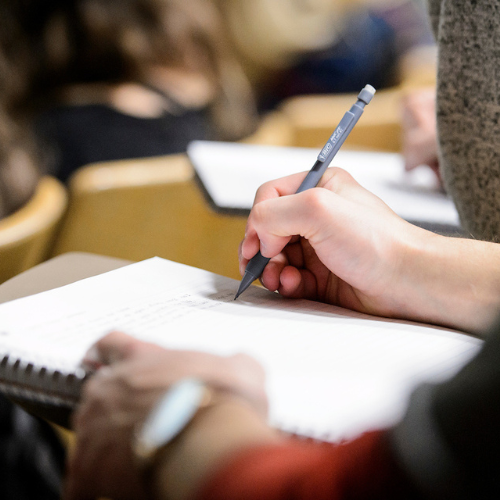 A hand writing in a notebook